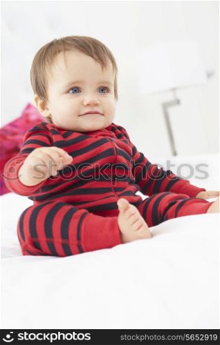 Toddler Sitting On Bed Wearing Pajamas