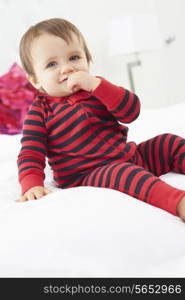 Toddler Sitting On Bed Wearing Pajamas