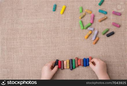 Toddlers hand putting crayons in line on canvas