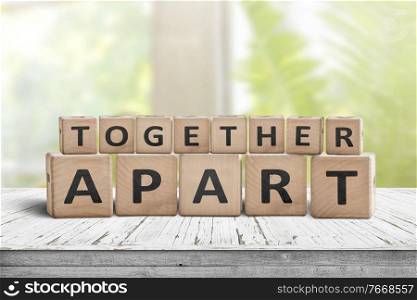 Together apart sign regarding social distancing at work and at home. Information on a worn table in a bright room with a window
