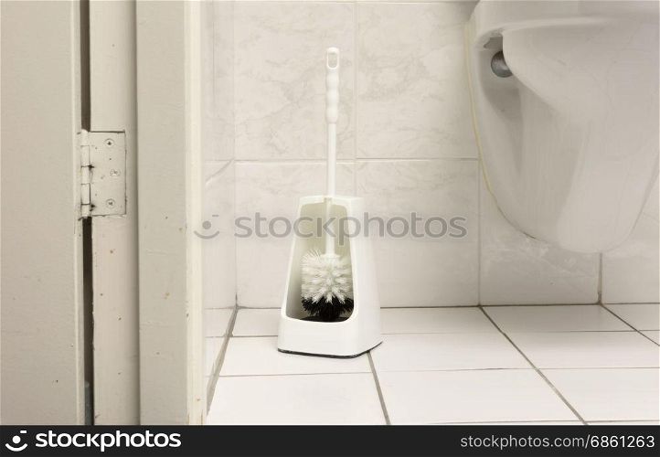 Toilet brush in a simple bathroom, white tiles