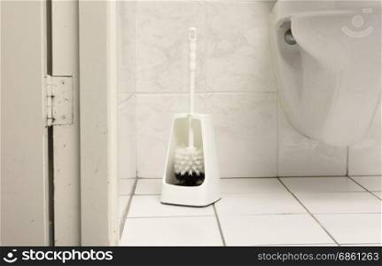 Toilet brush in a simple bathroom, white tiles