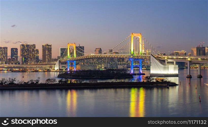 Tokyo city skyline at night with view of Rainbow bridge in Japan.
