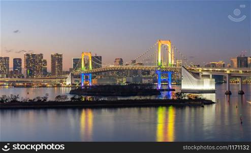 Tokyo city skyline at night with view of Rainbow bridge in Japan.