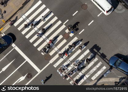 TOKYO, JAPAN - FEB 2019 : Top view of pedestrians crowd undefined people walking overpass the street intersection cross-walk with sunshine dat in tokyo on Febuary 16, 2019 in Tokyo, Japan