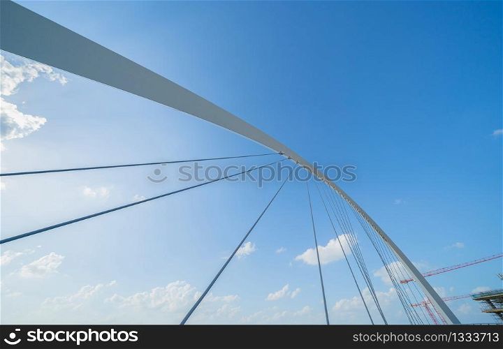 Tolerance bridge. Structure of architecture with lake or river, Dubai Downtown skyline, United Arab Emirates or UAE. Financial district and business area in urban city with blue sky background.