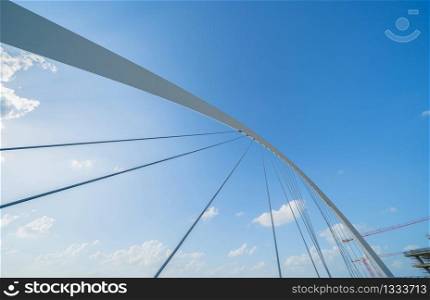 Tolerance bridge. Structure of architecture with lake or river, Dubai Downtown skyline, United Arab Emirates or UAE. Financial district and business area in urban city with blue sky background.