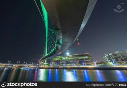 Tolerance bridge. Structure of architecture with lake or river, Dubai Downtown skyline, United Arab Emirates or UAE. Financial district and business area in urban city at night.