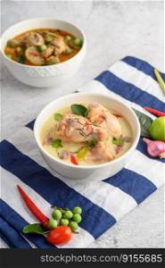 Tom Kha Kai in a bowl with kaffir lime leaves, lemongrass, red onion, galangal and chilli.Selective focus