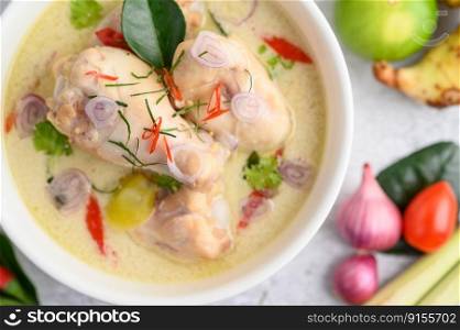 Tom Kha Kai in a bowl with kaffir lime leaves, lemongrass, red onion, galangal and chilli.Selective focus