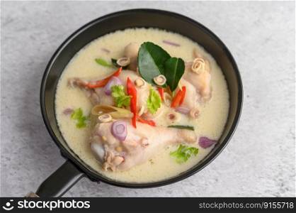 Tom Kha Kai in a pan frying with kaffir lime leaves, lemongrass, red onion, galangal and chilli.Selective focus.