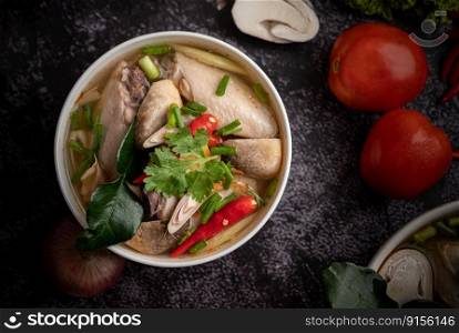 Tom yum chicken with chili, coriander, dried chili, kaffir lime leaves, mushroom and lemongrass in a bowl