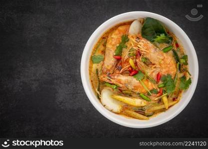 Tom Yum Goong, Tom Yum Kung, Thai food, hot and sour shrimp soup, creamy style in white ceramic bowl on dark tone texture background with copy space for text, top view