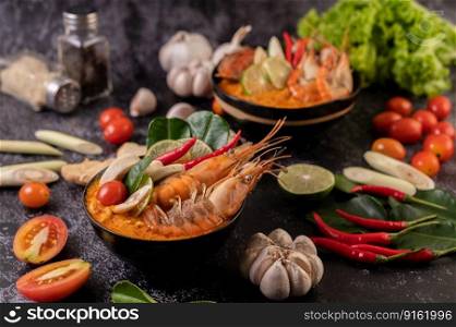 Tom Yum Kung in a bowl with tomato, chili, lemongrass, garlic, lemon, and kaffir lime leaves
