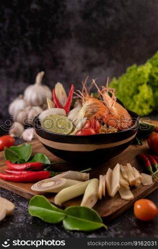 Tom Yum Kung in a bowl with tomato, chili, lemongrass, garlic, lemon, and kaffir lime leaves