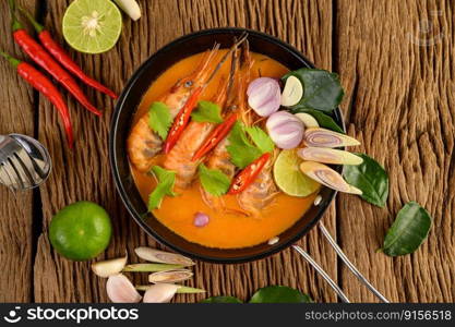 Tom Yum Kung Thai hot spicy soup shrimp with lemon grass,lemon,galangal and chilli on wooden background Thailand Food