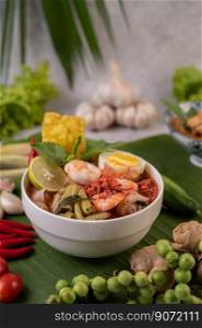 Tom Yum noodle with shrimp and boiled egg, accompanied by lime, cucumber, basil, eggplant and garlic.
