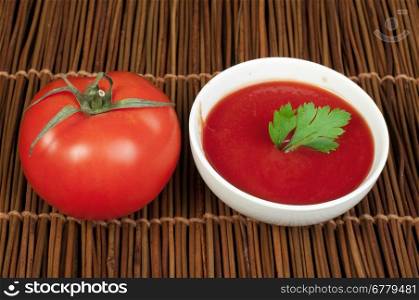Tomato and Bowl of tomato sauce on wooden base