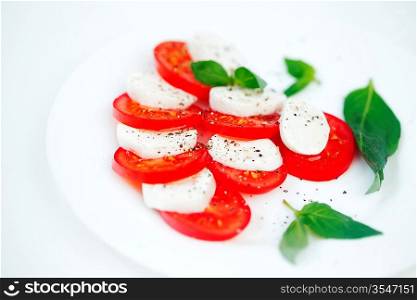 Tomato and mozzarella with basil leaves on a plate