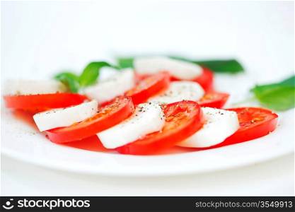 Tomato and mozzarella with basil leaves on a plate