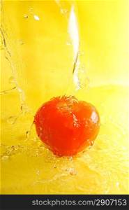 Tomato and water splashes on yellow close up