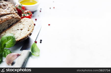 Tomato, bread, basil and olive oil on white marble background. Italian cooking, healthy food or vegetarian concept