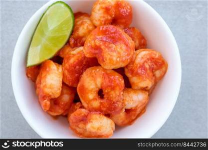 Tomato garlic shrimp with lime wedge in bowl