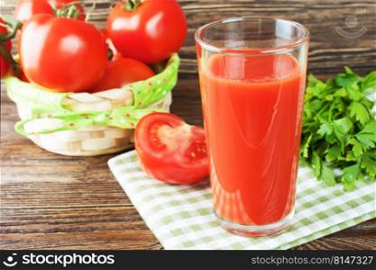 Tomato juice in a glass, and fresh tomatoes on brown wooden backround. Tomato juice and fresh tomatoes