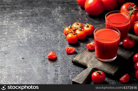 Tomato juice in a glass on a cutting board. On a black background. High quality photo. Tomato juice in a glass on a cutting board.