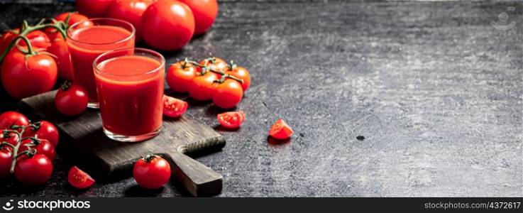 Tomato juice in a glass on a cutting board. On a black background. High quality photo. Tomato juice in a glass on a cutting board.