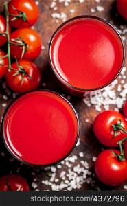 Tomato juice in a glass with pieces of salt. On a wooden background. High quality photo. Tomato juice in a glass with pieces of salt.