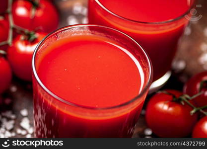 Tomato juice in a glass with pieces of salt. On a wooden background. High quality photo. Tomato juice in a glass with pieces of salt.