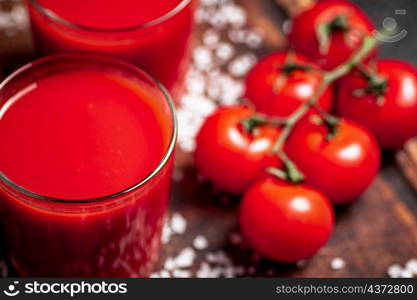 Tomato juice in a glass with pieces of salt. On a wooden background. High quality photo. Tomato juice in a glass with pieces of salt.