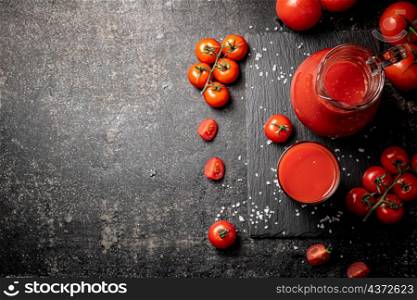 Tomato juice on a stone board with pieces of salt. On a black background. High quality photo. Tomato juice on a stone board with pieces of salt.