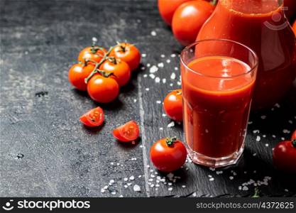 Tomato juice on a stone board with pieces of salt. On a black background. High quality photo. Tomato juice on a stone board with pieces of salt.