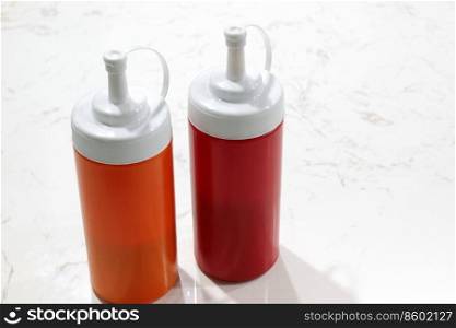 tomato ketchup and chilli sauce in plastic bottle on white table