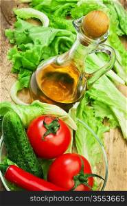 Tomato, lettuce salad and jug of vegetable oil on a wooden table