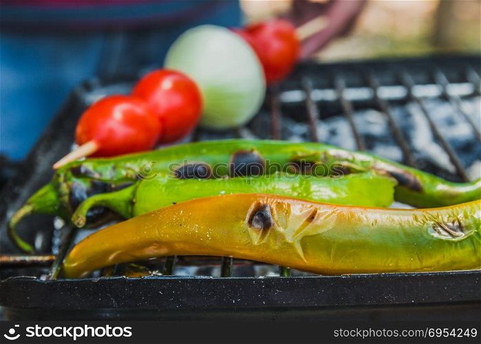 Tomato, onion and green chili pepper are cooked on the grill.