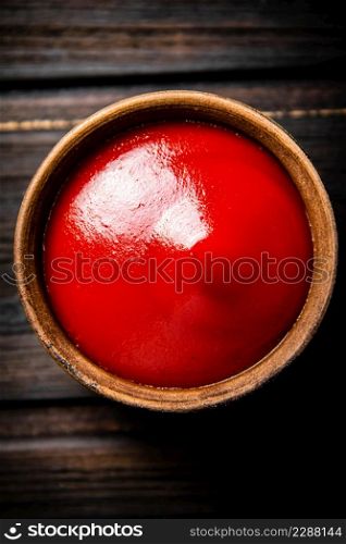 Tomato sauce in a bowl on the table. On a wooden background. Top view. High quality photo. Tomato sauce in a bowl on the table.