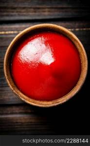 Tomato sauce in a bowl on the table. On a wooden background. Top view. High quality photo. Tomato sauce in a bowl on the table.