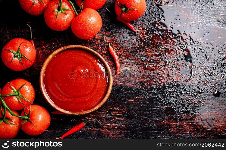 Tomato sauce in a plate with red pepper trays. Against a dark background. High quality photo. Tomato sauce in a plate with red pepper trays.