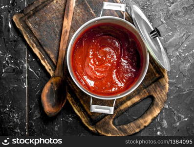 Tomato sauce in a pot on a cutting Board. On rustic background. Tomato sauce in a pot on a cutting Board.