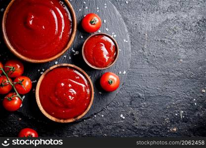 Tomato sauce in a wooden plate. On a black background. High quality photo. Tomato sauce in a wooden plate.