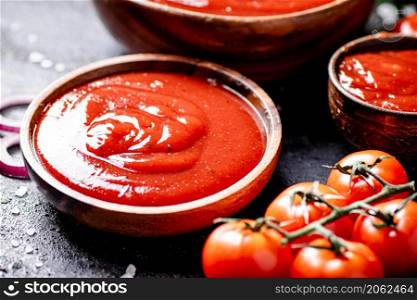 Tomato sauce in a wooden plate. On a black background. High quality photo. Tomato sauce in a wooden plate.