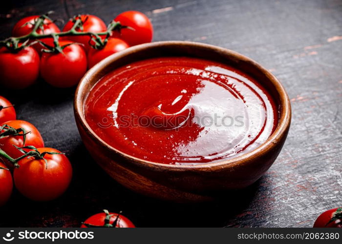 Tomato sauce in a wooden plate. On the dark background. High quality photo. Tomato sauce in a wooden plate.