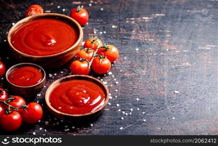 Tomato sauce in wooden plates with pieces of salt. Against a dark background. High quality photo. Tomato sauce in wooden plates with pieces of salt.