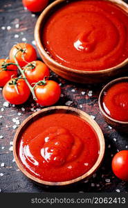 Tomato sauce in wooden plates with pieces of salt. Against a dark background. High quality photo. Tomato sauce in wooden plates with pieces of salt.