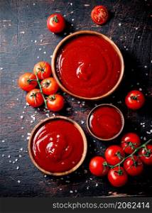 Tomato sauce in wooden plates with pieces of salt. Against a dark background. High quality photo. Tomato sauce in wooden plates with pieces of salt.