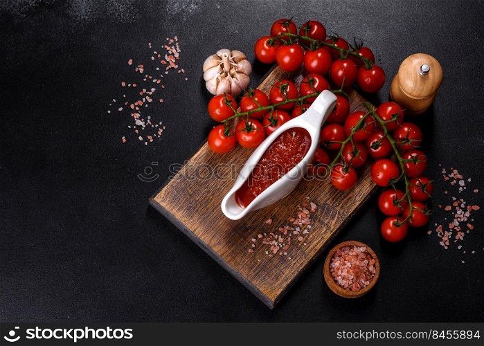 Tomato Sauce on a vintage background as detailed close-up shot. Spicy seasoning of Georgian cuisine adjika in a bowl with red omatoes on a concrete table close-up