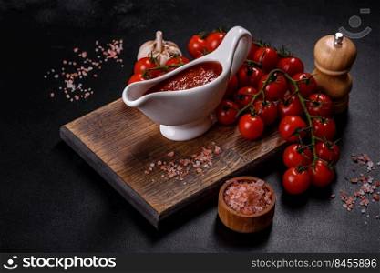 Tomato Sauce on a vintage background as detailed close-up shot. Spicy seasoning of Georgian cuisine adjika in a bowl with red omatoes on a concrete table close-up